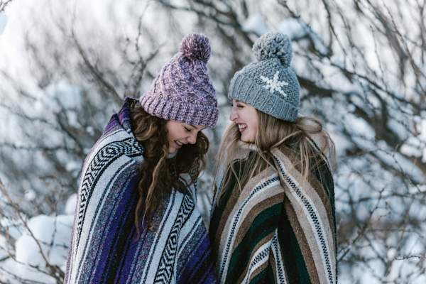 two women in winter clothes talking and laughing