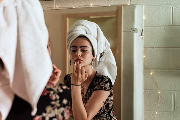 Woman applying makeup with towel wrapped around her head