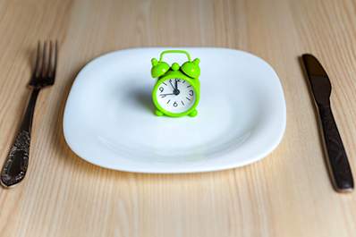 Fasting, alarm clock on a plate concept