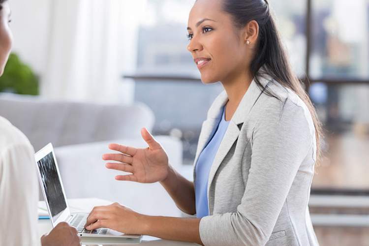 Doctor on laptop talking to woman patient.