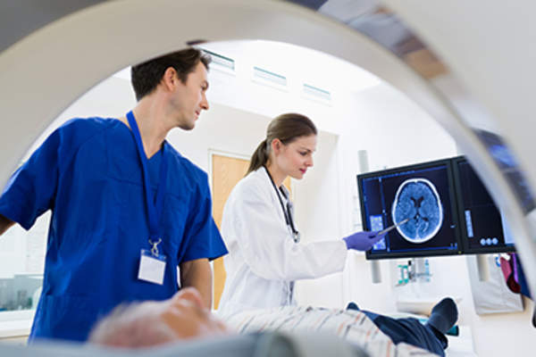 Two doctors with a patient in an MRI machine.