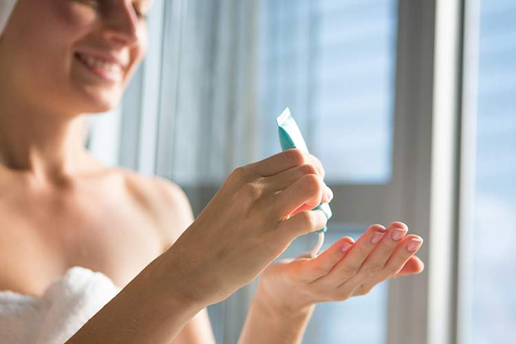 Woman squeezing ointment onto her hands after a shower.