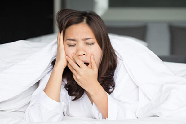 Sleepy asian woman yawning in bed at home
