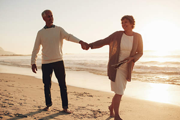 Happy mature couple walking along the beach.