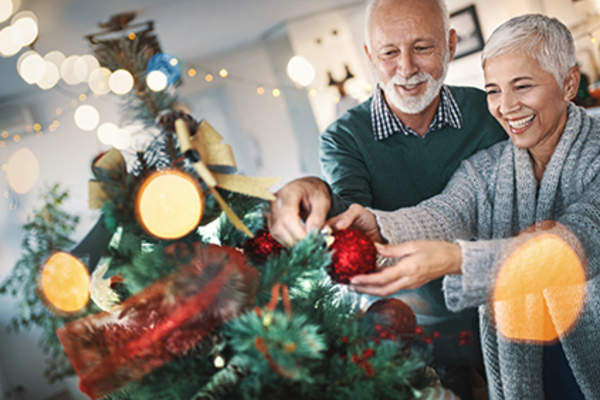 Senior couple putting ornaments on a Christmas tree.