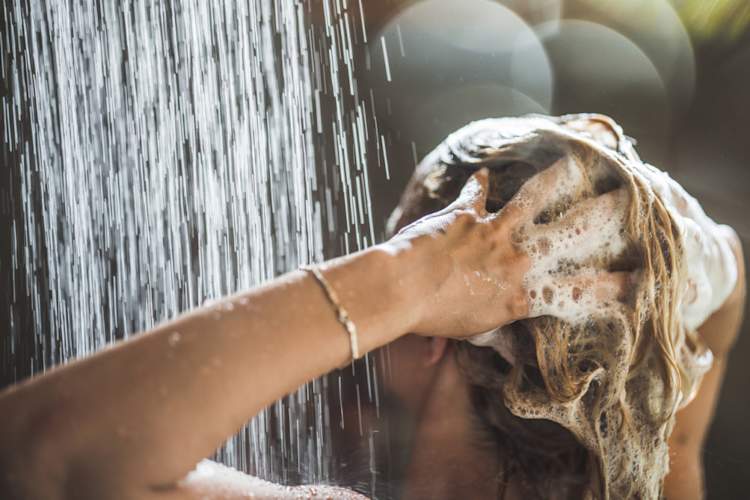 Woman washing her hair with shampoo in the shower
