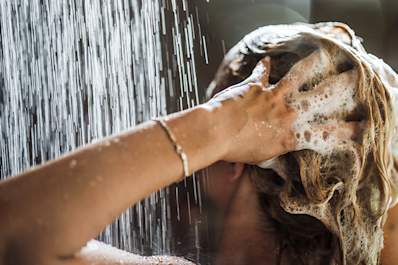 Woman washing her hair with shampoo in the shower