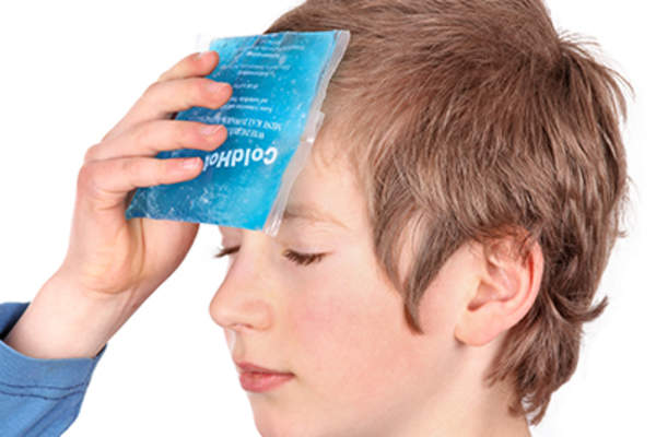 Woman with headache holding ice pack to forehead.