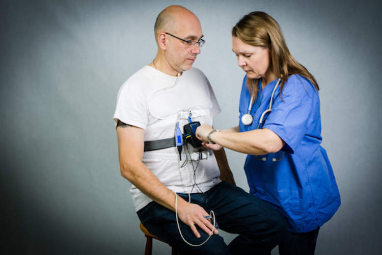 Nurse setting up sleep apnea monitor on male patient.