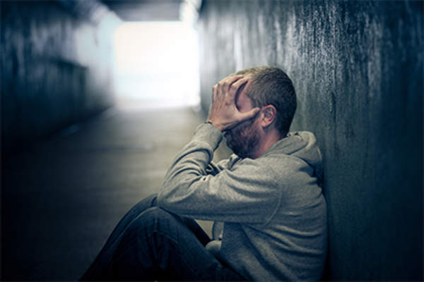 Homeless man sitting in alley.