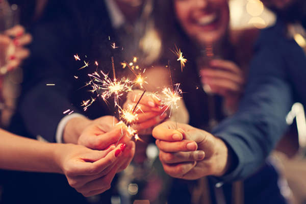 Friends holding sparklers together.