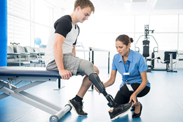 Physical therapist helping man with prosthetic leg.