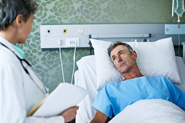 Man in a hospital bed talking to a doctor.