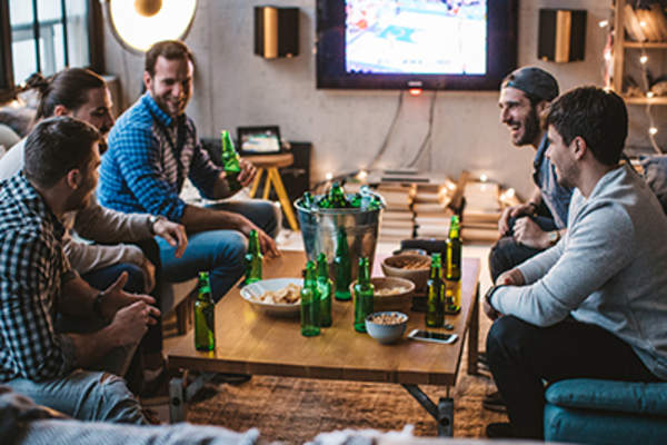 Group of men talking while watching sports and eating snacks.