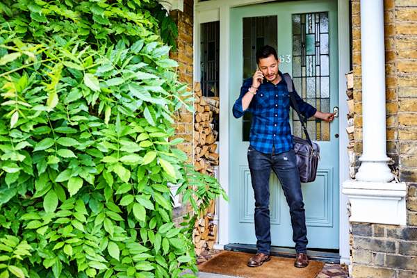 man leaving the house and talking on the phone