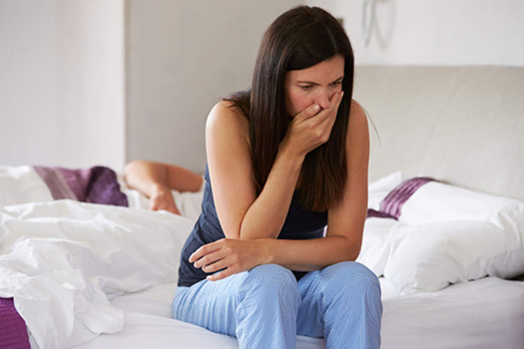 Woman waking up in the morning and experiencing nausea.