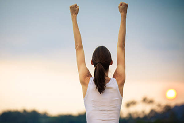 Woman with her hands raised in the air victoriously.