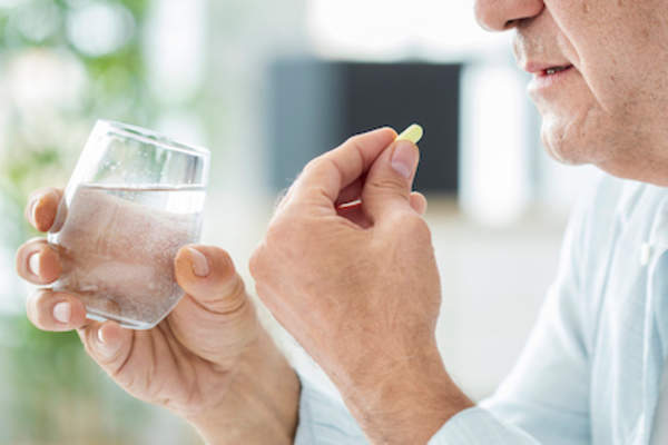 older man taking medication.