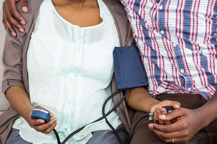 Couple at home, woman taking her blood pressure.