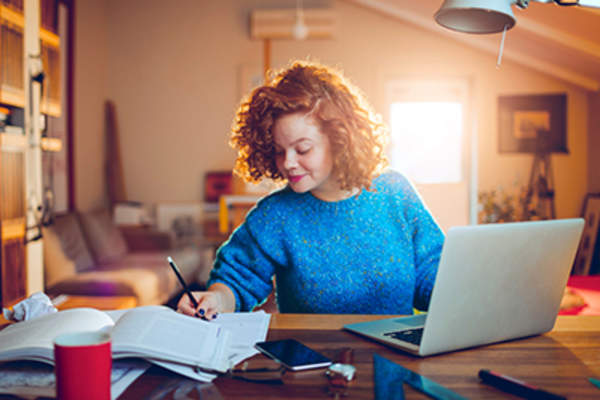 Woman doing research with her laptop and taking notes.