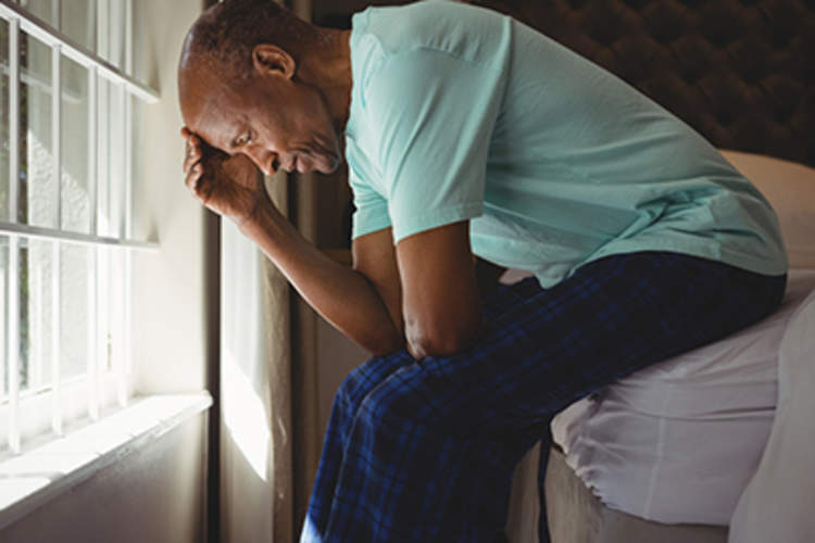 Worried man sitting on the edge of a bed.