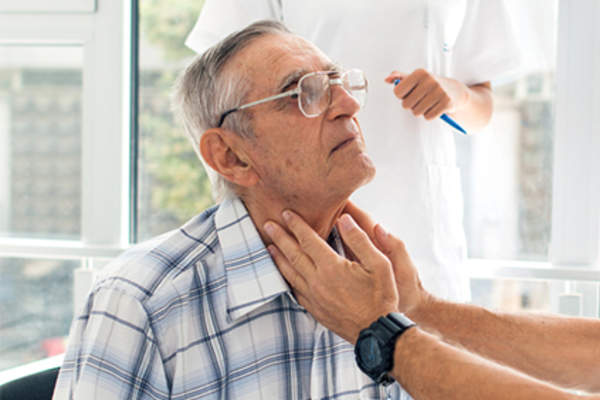 Doctor checking lymph nodes in neck in senior man.