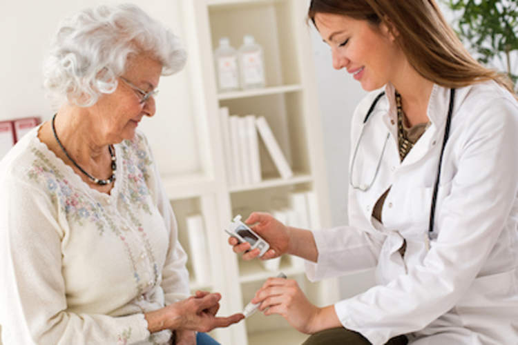 A doctor helps an elderly woman check her blood glucose level.