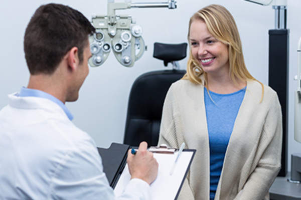 Smiling female patient talking to eye doctor at exam.