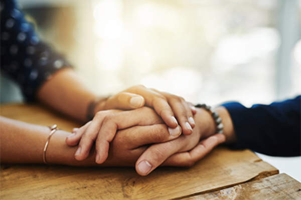 Woman holding another's hand in comfort.
