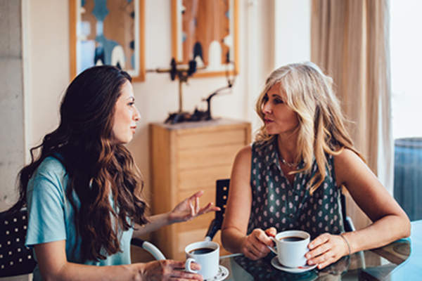 Women talking at a table drinking coffee.