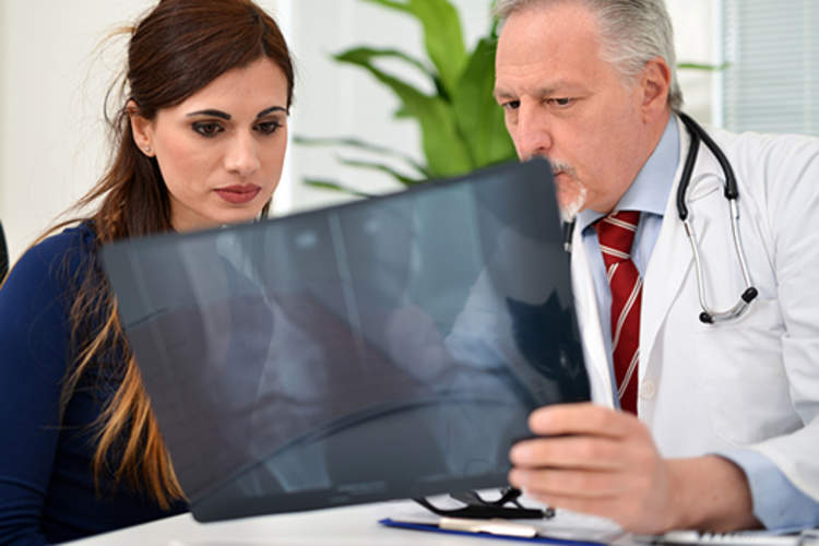 Doctor and woman looking at knee x-rays.
