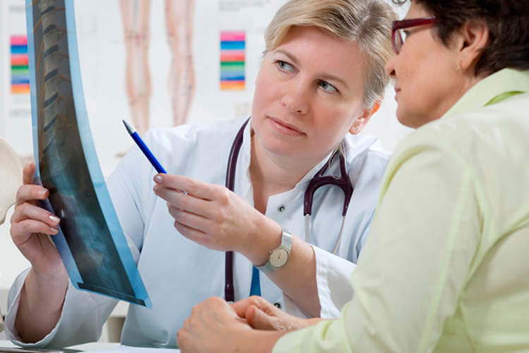 Doctor reviews spinal X-ray with patient.