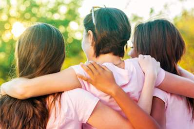 Young women embrace after a cancer awareness walk fundraiser.