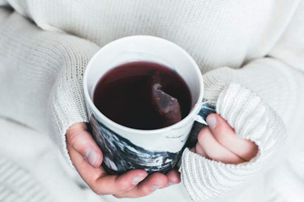 person in sweater holding tea
