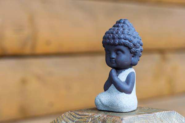 Tiny Buddha statue on wooden block.