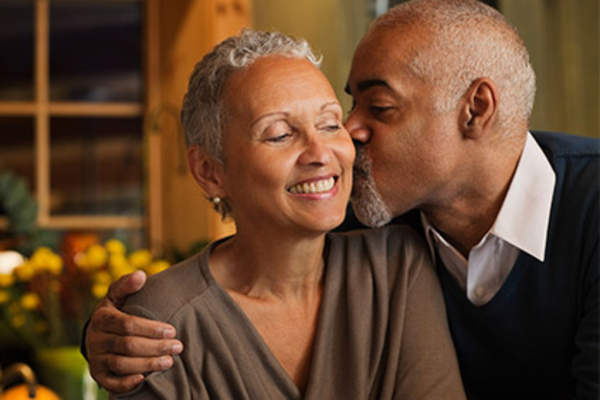 Senior man gently kissing his wife's cheek.