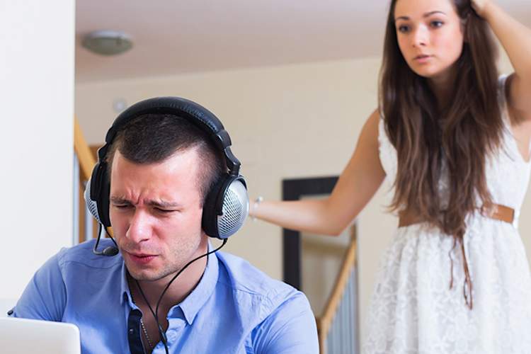 Man using laptop while woman is upset behind him.