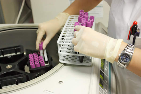 Tech loading centrifuge with blood samples.