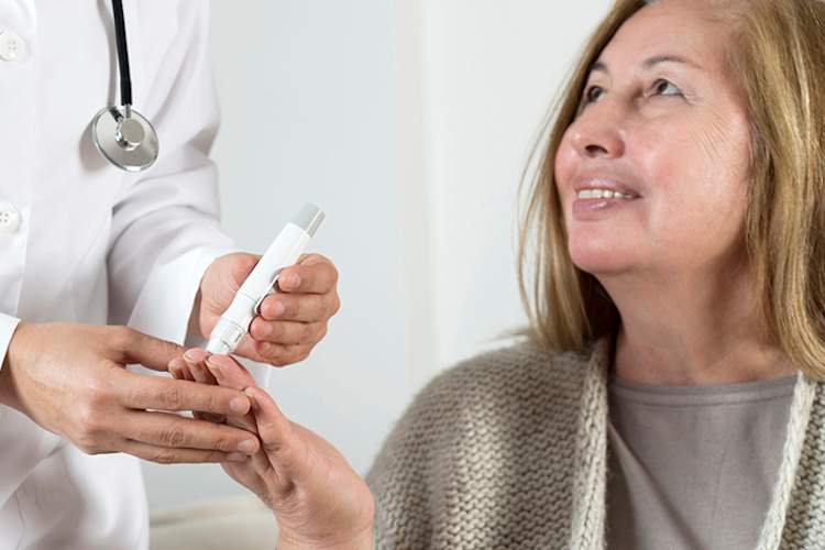 Diabetologist checking woman's blood sugar.
