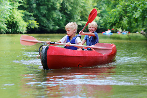 Two boys kayaking on a river.