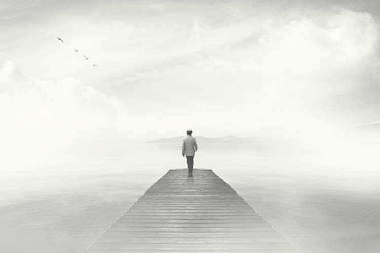Man walking on boardwalk in fog.