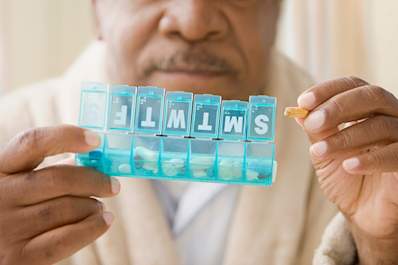 Senior man holding a pill organizer