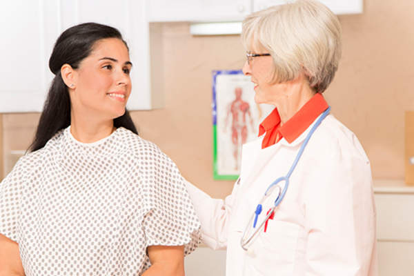 Young woman with doctor before breast exam image.