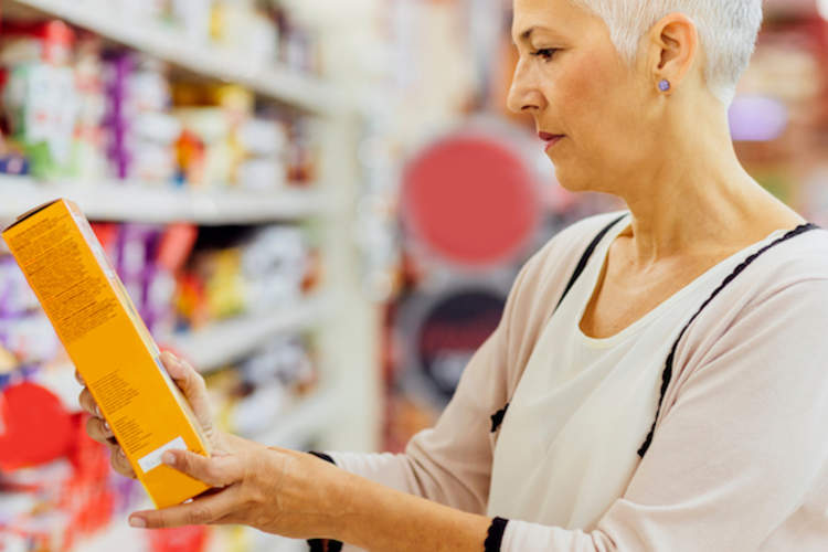 A woman reading nutrition labels in a grocery store.