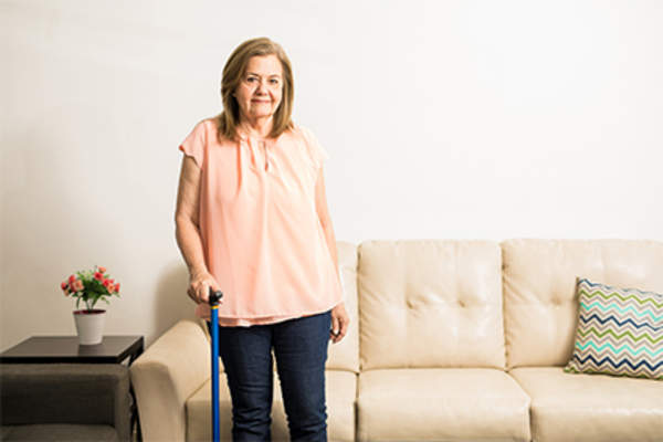Woman using walking cane in living room at home.
