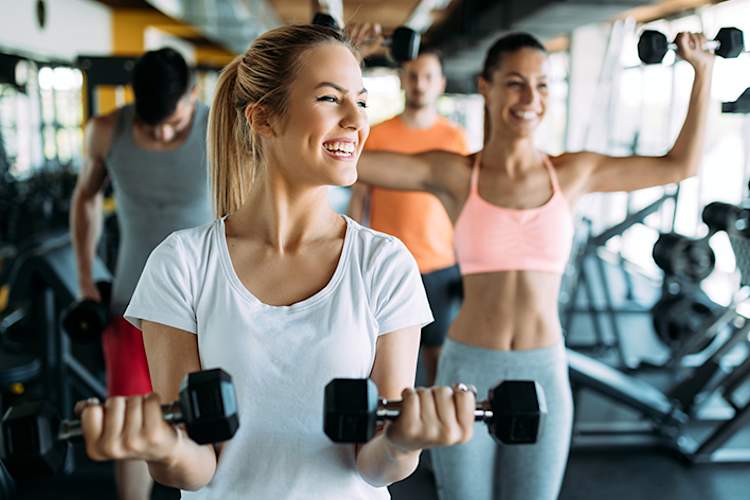 Smiling young women exercising at gym.