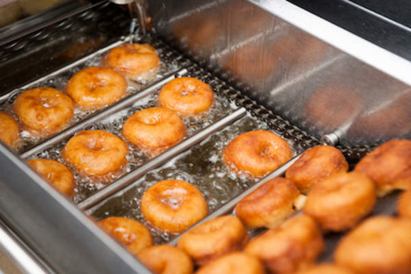 Deep frying donuts in baker factory.