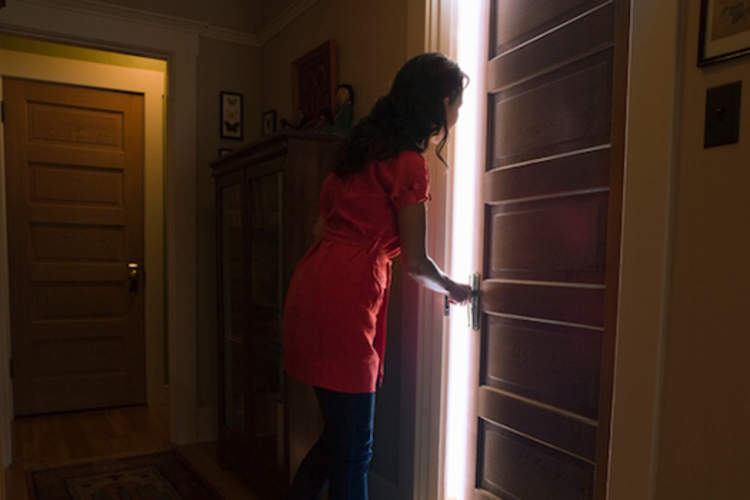 Woman opening door to bedroom.