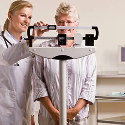 Senior woman being weighed by her doctor.