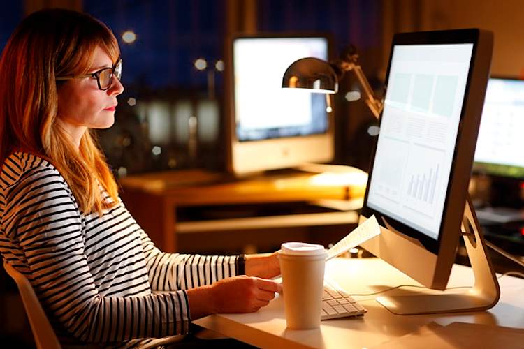 Woman working at her computer and desk late at night.